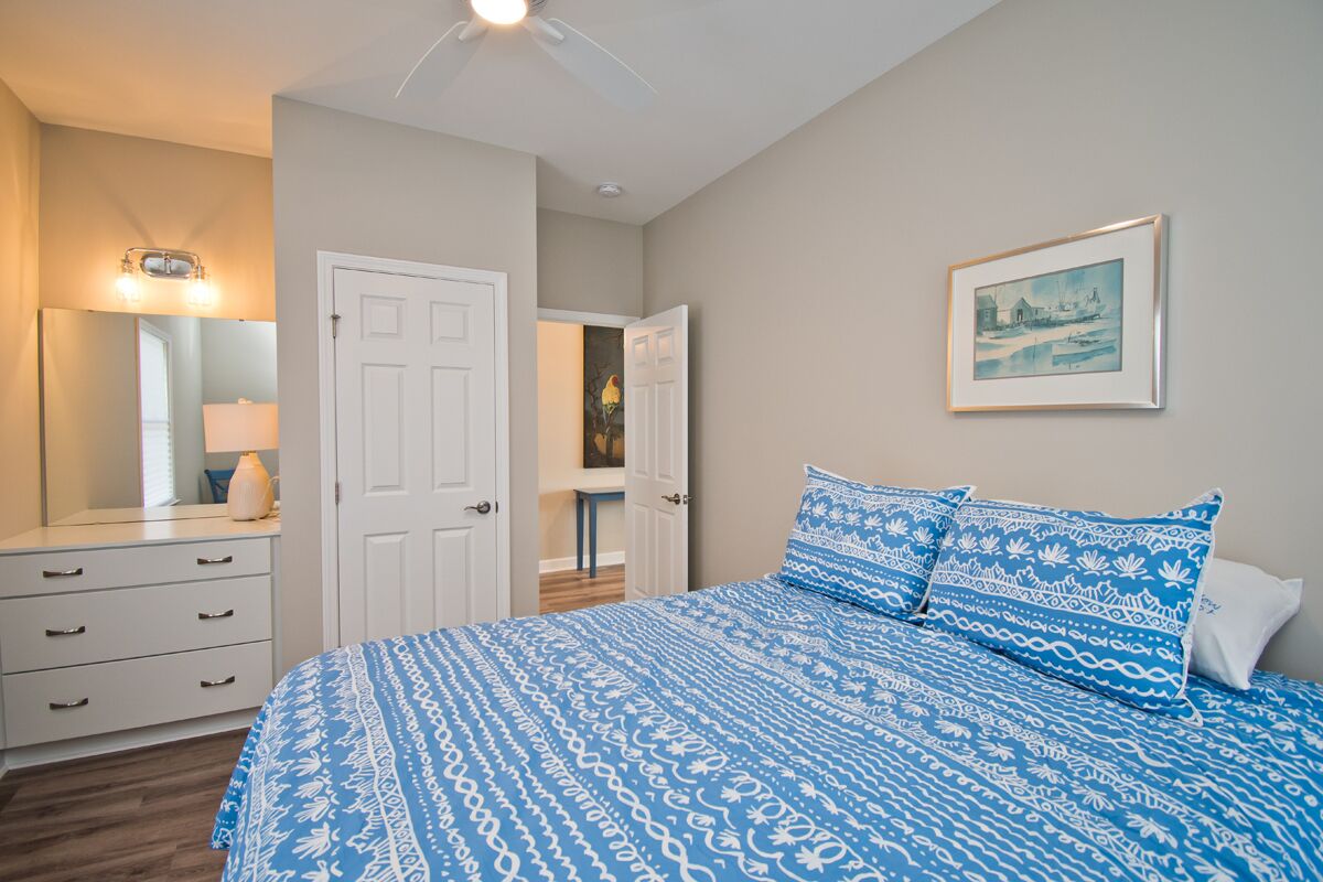 A bedroom with a bed, a dresser, a door, and a framed picture on the wall.