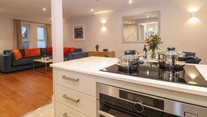 Eine moderne Küche mit Einbauherd, ein Essbereich mit Tisch und Stühlen sowie ein Wohnzimmer mit Sofa und Couchtisch.