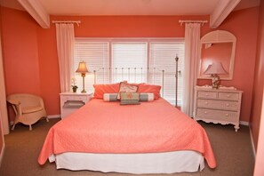 A bedroom with a large bed, white nightstands, a dresser, and a chair. - Viewpoint, Oceanfront House in Emerald Isle, NC! (Emerald Isle)