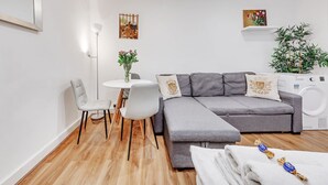 A modern living room with a grey sofa, white chairs, a small round table, and a washing machine. - Central London apartment (London)