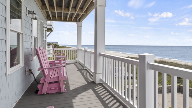 A wooden deck with white railings, a covered area with a wooden ceiling, and a view of the ocean. - Blue View, Oceanfront House in Pine Knoll Shores, NC! (Pine Knoll Shores)