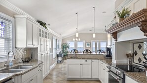 A spacious kitchen with white cabinetry, granite countertops, and a large island. - Blue View, Oceanfront House in Pine Knoll Shores, NC! (Pine Knoll Shores)