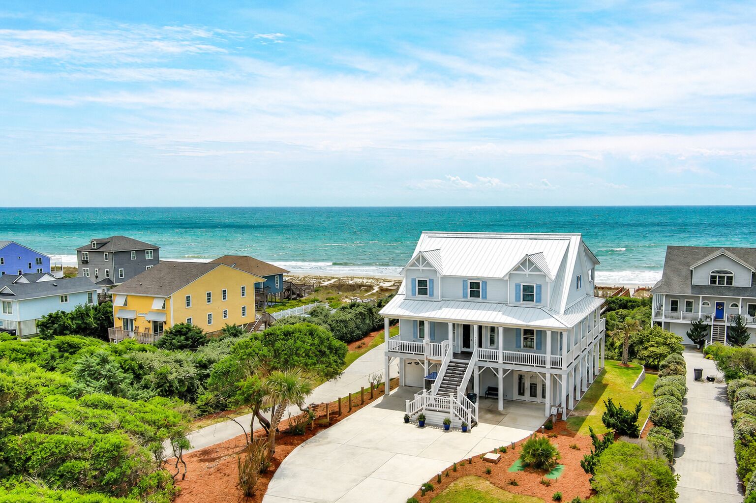A coastal house with a porch, a staircase, and a view of the ocean.