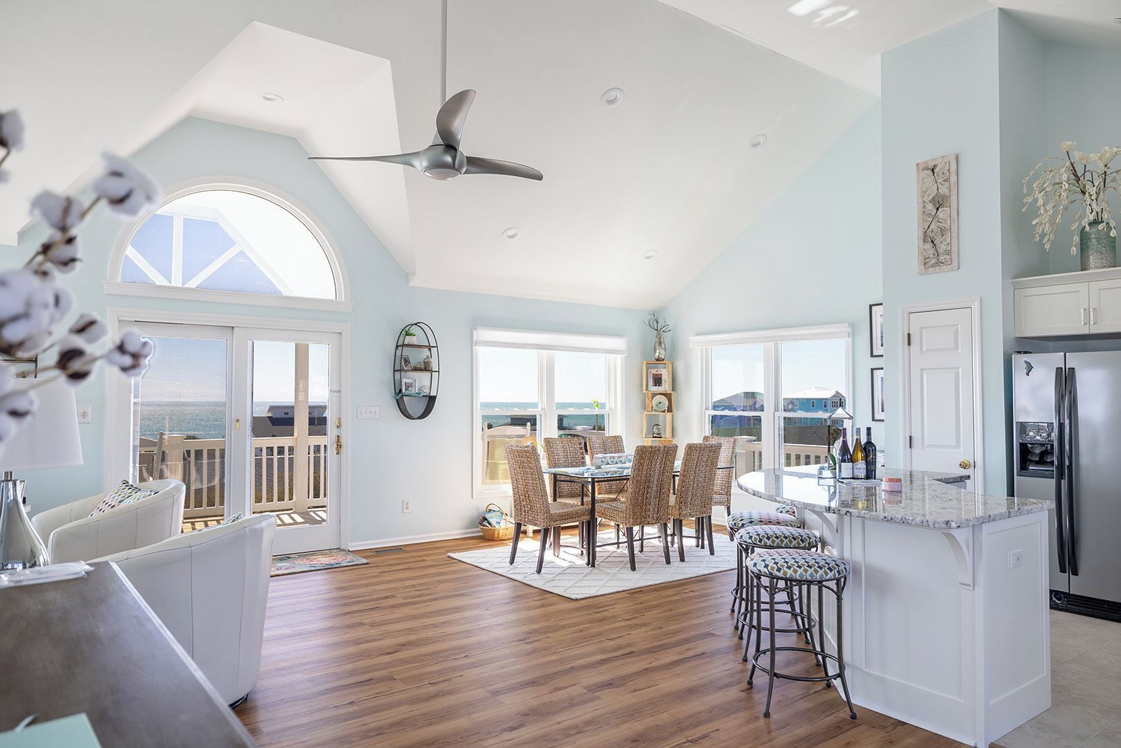 A spacious kitchen with a large island, a dining area with a round table and chairs, and a ceiling fan.