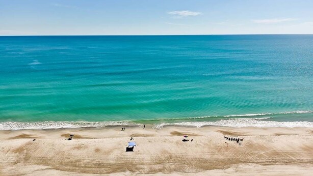 Een strand met helder turquoise water en een zandstrand.