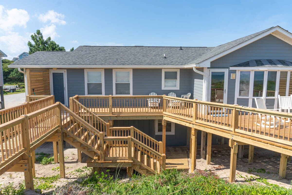 A two-story house with a wooden deck, a covered outdoor area, and a small porch.