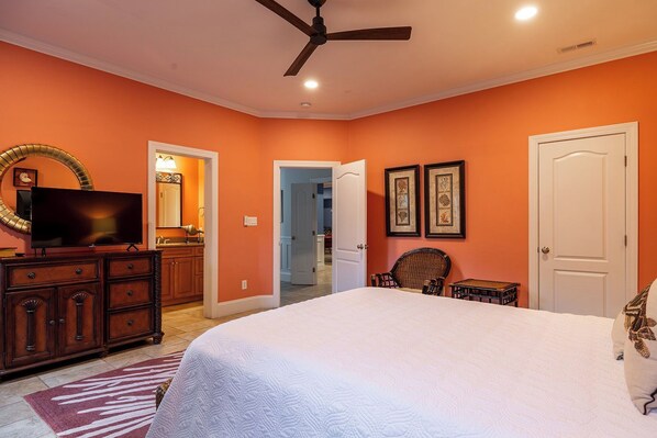 Une chambre à coucher comprenant un lit, une commode, un téléviseur et un ventilateur de plafond.