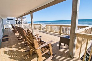 A wooden deck with rocking chairs and a table overlooking the ocean.