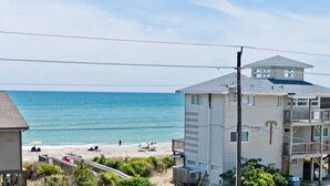 A coastal building with a balcony overlooking the beach, a clear view of the ocean, and a sandy beach in the background. - Cardinal's Landing, Almost Oceanfront House in Emerald Isle, NC! (Emerald Isle)