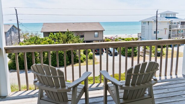 A wooden deck with two Adirondack chairs facing a beach view. - Cardinal's Landing, Almost Oceanfront House in Emerald Isle, NC! (Emerald Isle)