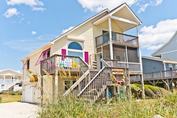 A two-story house with a balcony, a garage, and a visible staircase. - Cardinal's Landing, Almost Oceanfront House in Emerald Isle, NC! (Emerald Isle)