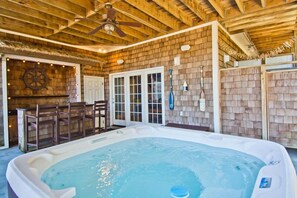 A hot tub in a rustic cabin with wooden walls, a ceiling fan, and a bar area with chairs. - Carolina, Oceanside House in Emerald Isle, NC! (Emerald Isle)