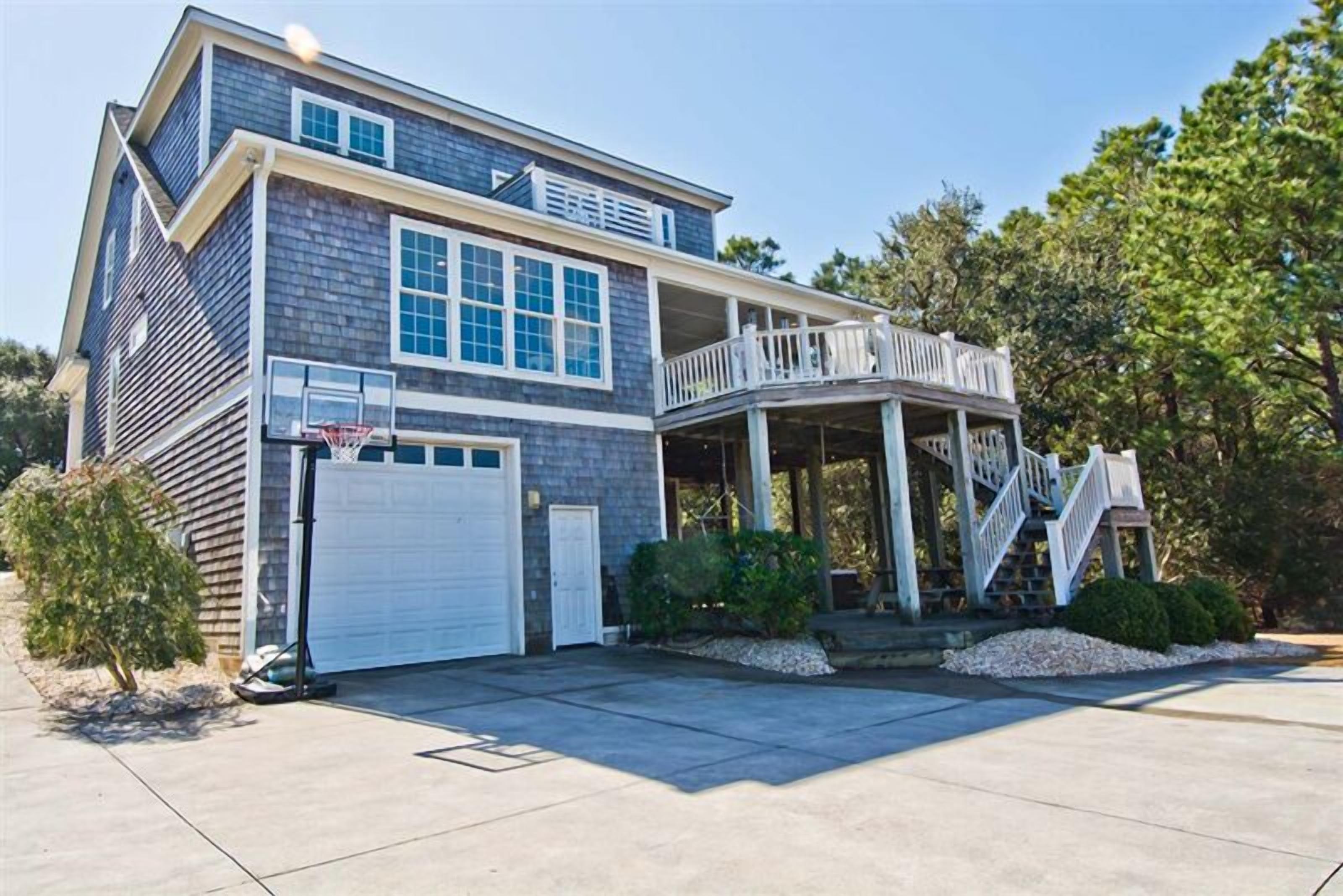 A two-story house with a covered porch, a garage, and a basketball hoop.