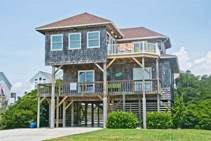 A two-story house with a wooden deck and a balcony.