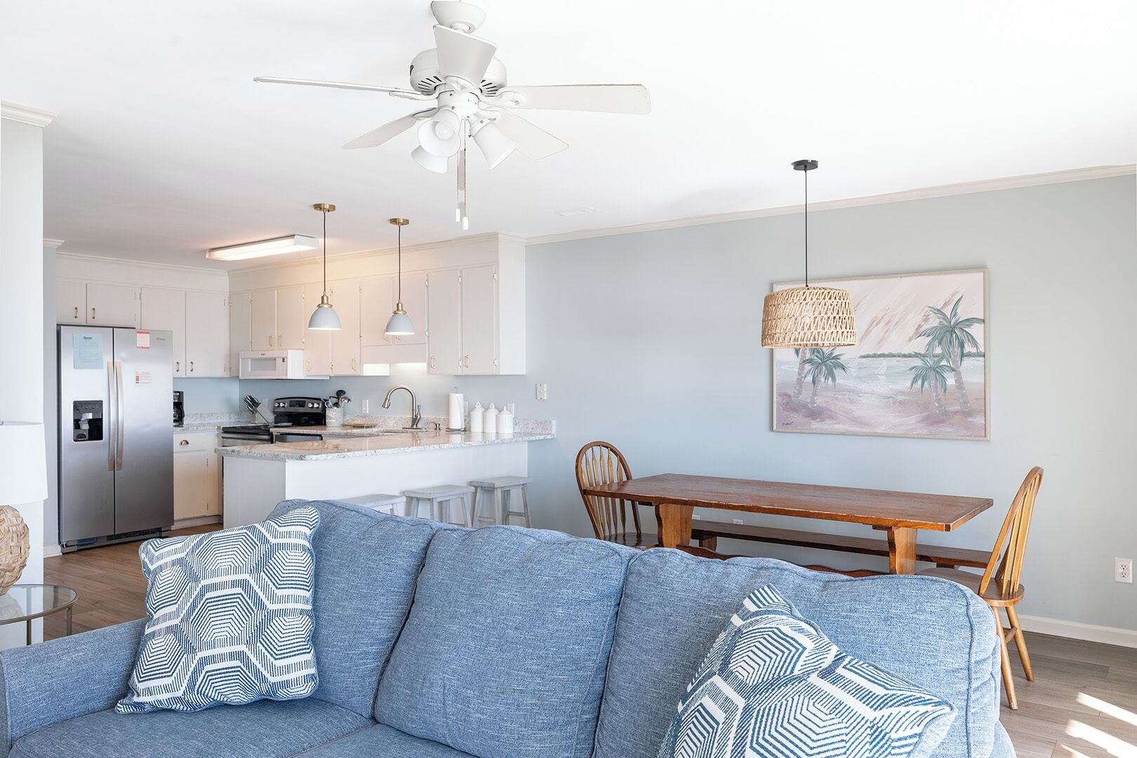A modern kitchen with white cabinets, a stainless steel refrigerator, and pendant lighting.