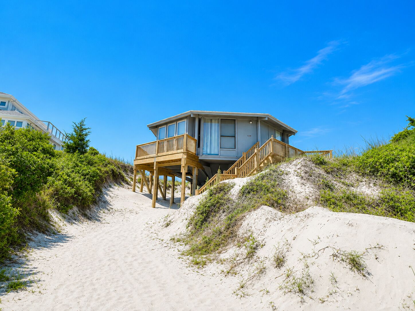 A beachfront property with a wooden deck and a large windowed structure.