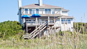 A two-story house with a porch, wooden stairs, and blue umbrellas. - Casa Atlantica, Oceanfront House in Pine Knoll Shores, NC! (Pine Knoll Shores)