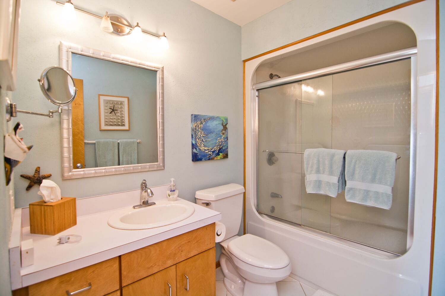 Un bagno con lavandino, specchio, servizi igienici e cabina doccia in vetro.