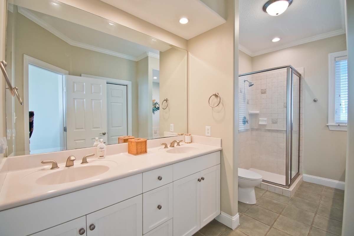 A modern bathroom with a large mirror, dual sinks, and a walk-in shower.