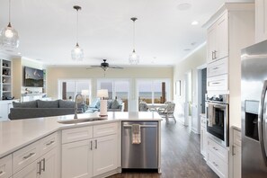 A modern kitchen with a central island, stainless steel appliances, and pendant lighting. - Casa Del Sole, Oceanfront House in Emerald Isle, NC! (Emerald Isle)