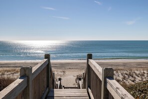 Une promenade en bois qui mène à une plage d’où l’on a une vue dégagée sur l’océan.