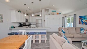 A modern kitchen with white cabinets, a central island, and pendant lighting. - Chillin' The Most, Oceanview House in Emerald Isle, NC! (Emerald Isle)