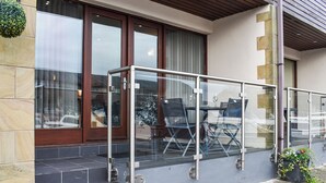 A glass-enclosed outdoor seating area with a table and chairs, a door with a glass panel, and a potted plant. - 2 bedroom accommodation in Carnforth (Carnforth)