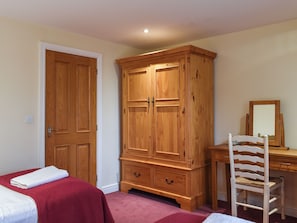 A bedroom with a wooden wardrobe, a desk with a mirror, and a chair. - 2 bedroom accommodation in Carnforth (Carnforth)