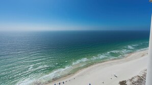A beach with clear blue water, a sandy shore, and a few people.