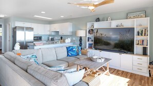A modern living room with a grey sofa, wooden coffee table, and a flat-screen TV. - Angel's at the Pier West - Oceanfront Duplex in Emerald Isle, NC! (Emerald Isle)