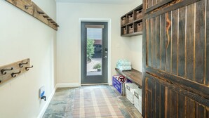 Un couloir avec une porte en bois, un sol à carreaux et une étagère avec des paniers.