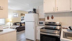 Cocina compacta con refrigerador, microondas, horno y cafetera sobre la encimera.
