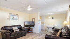 Una sala de estar con dos sofás de cuero, un televisor y un comedor con mesa y sillas.