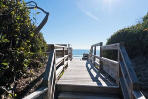 A wooden boardwalk leading to a beach with a clear sky. - Coral Shores #11, Oceanfront Condo in Pine Knoll Shores, NC! (Pine Knoll Shores)