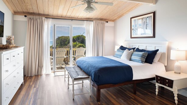 Un dormitorio con cama, mesita de noche, una silla, cómoda y vistas al exterior.