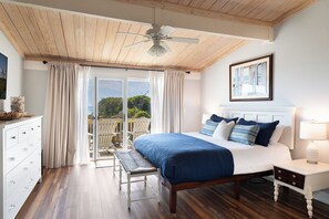 A bedroom with a bed, a nightstand, a chair, a dresser, and a view of the outdoors.