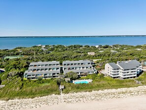 A coastal hotel with multiple buildings, a swimming pool, and a view of the ocean.