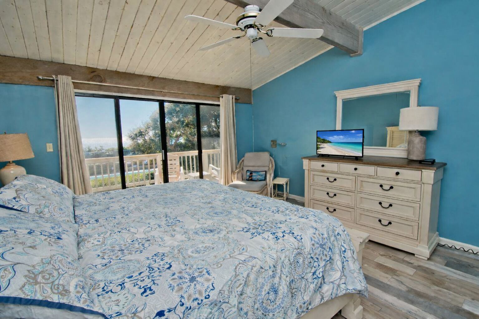 Ein Schlafzimmer mit einem großen Bett, einem Schminktisch, einem Fernseher und einem Balkon mit Aussicht.