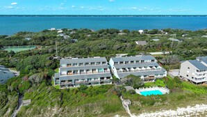 A coastal hotel with multiple buildings, a swimming pool, and a view of the sea.