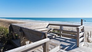 A wooden boardwalk leading to a beach with a clear view of the ocean.