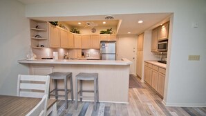 A modern kitchen with a central island, wooden cabinets, and a microwave.