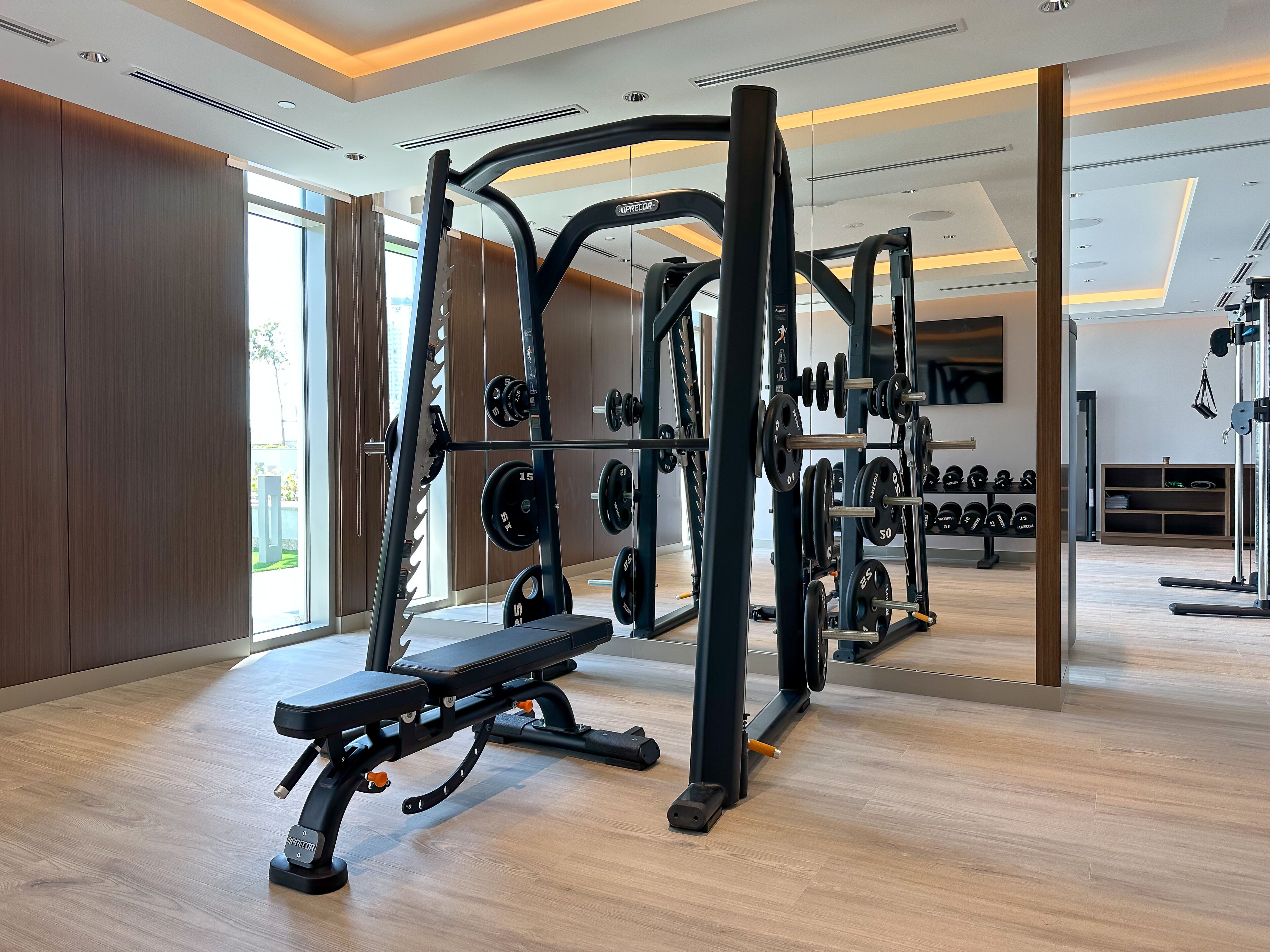 Een moderne sportschool met diverse fitnessapparaten, waaronder een bankdrukapparaat en gewichtrekken.