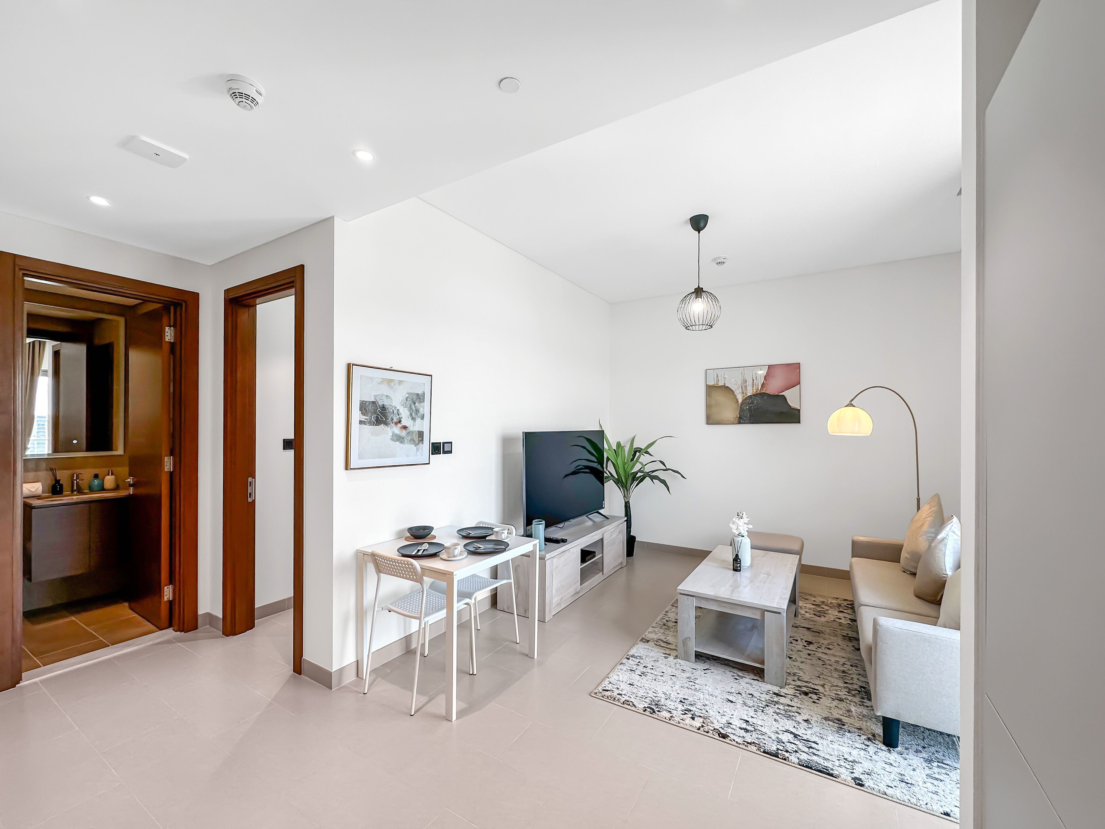 A modern living room with a TV, sofa, coffee table, and dining area.