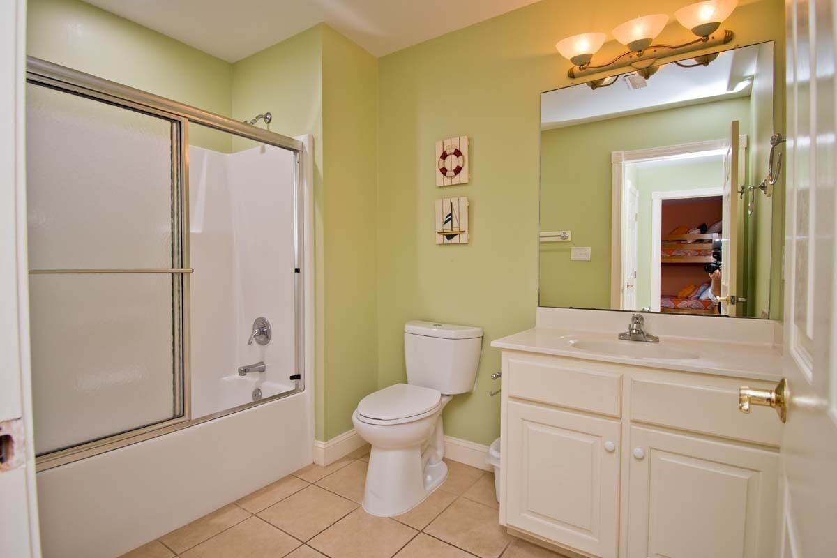 A bathroom with a glass-enclosed shower, a toilet, and a vanity with a mirror.