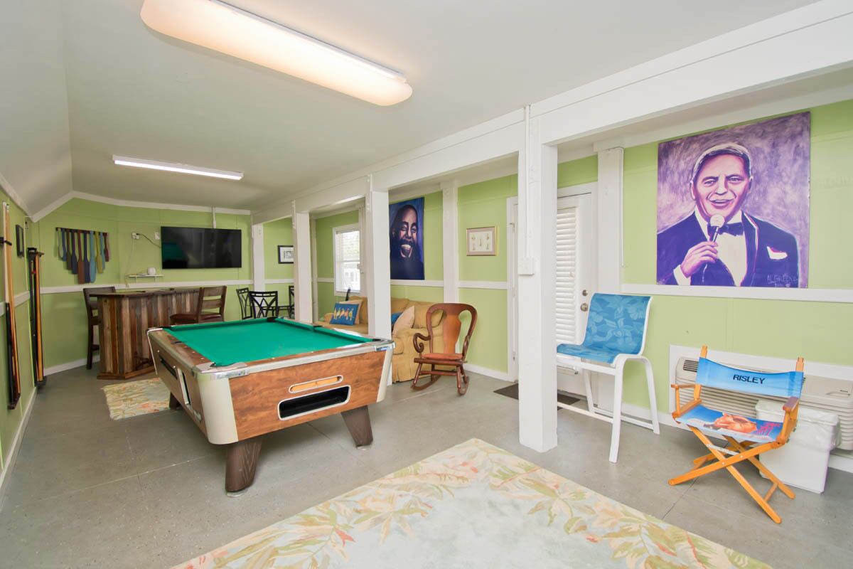 A pool room with a pool table, chairs, and a folding chair.