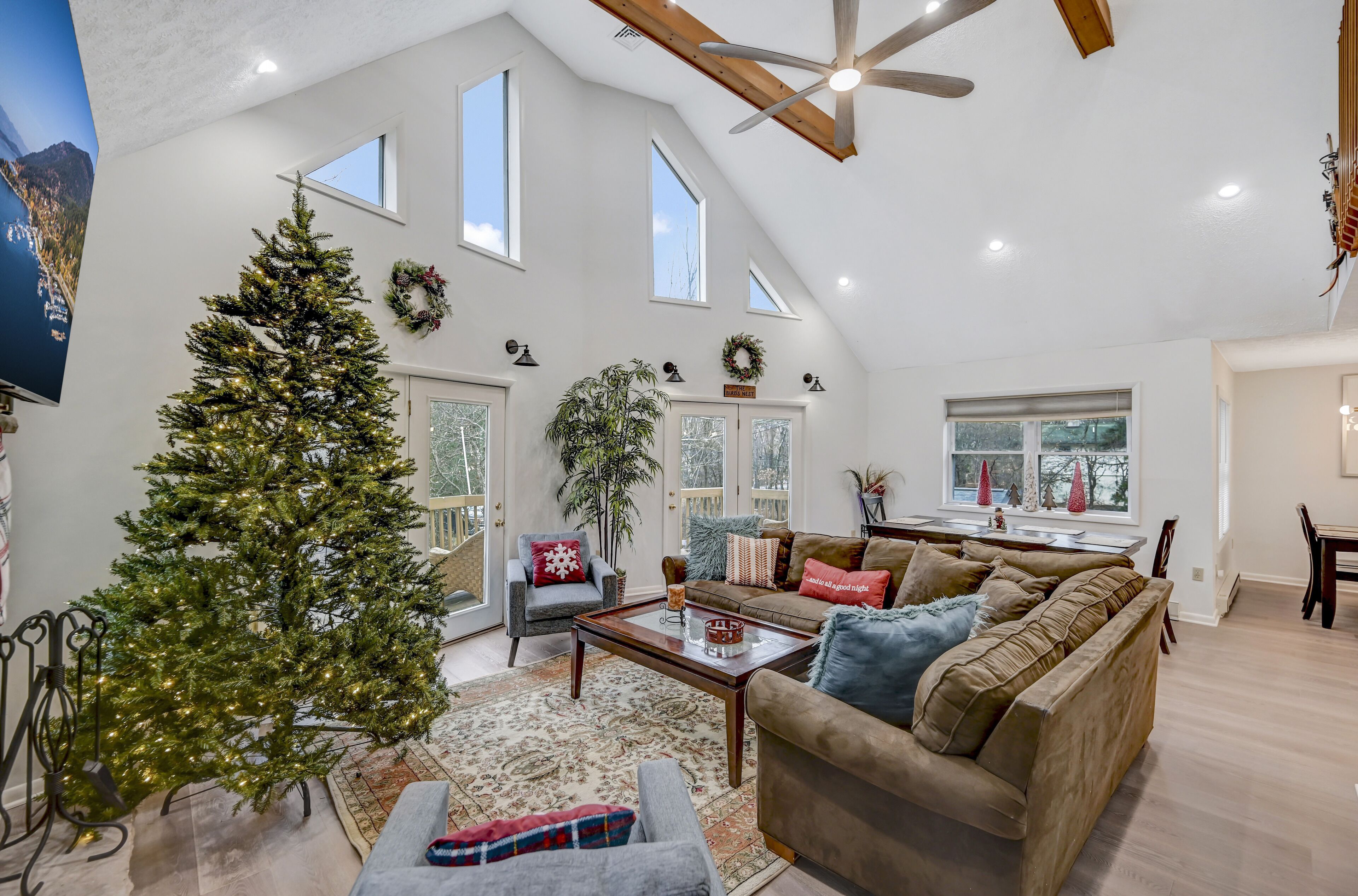 A spacious living room with a large Christmas tree, a cozy sofa, and a dining area.