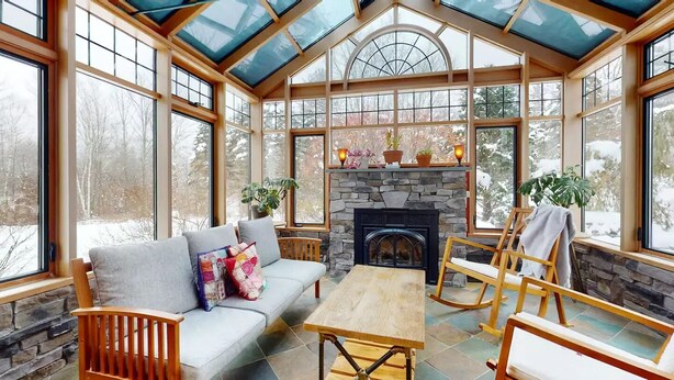 A cozy room with a stone fireplace, a sofa, a table, and wooden rocking chairs.