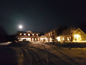 Une grande maison à deux étages, avec une allée enneigée et un garage bien visible.