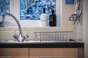 Un lavamanos de cocina con un grifo moderno, una botella de detergente para platos y un dispensador de jabón para manos.