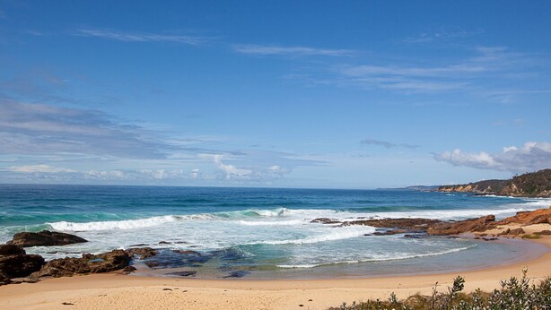 A beach with clear blue water, rocky shoreline, and a sandy beach. - Beachview 2 - Scenic Drive 33 (Bermagui)